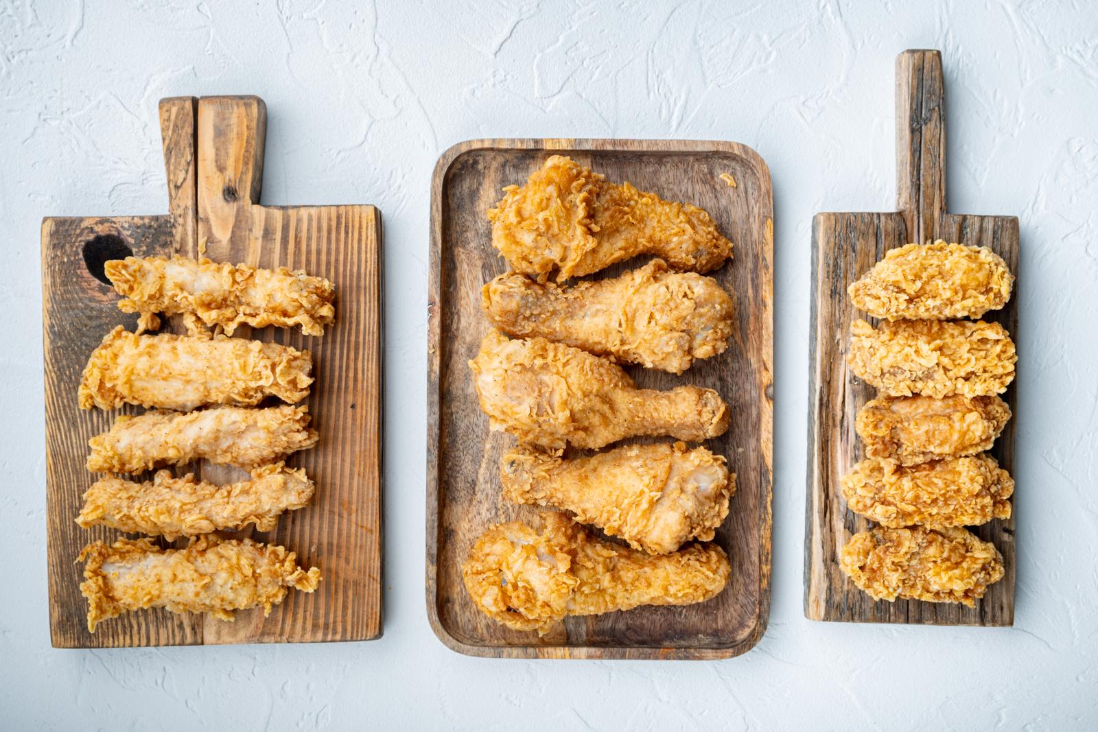 Breaded fried chicken parts on white background, top view.