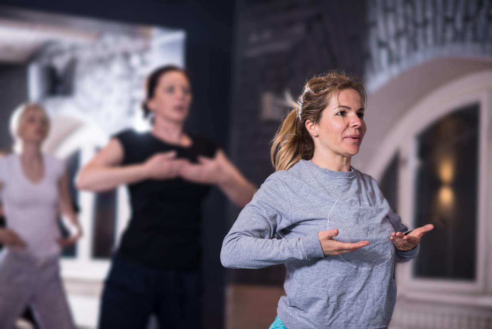 group of young healthy sporty women working out with instructor doing aerobics exercises in a fitness studio fitness, sport, training, gym and lifestyle concept